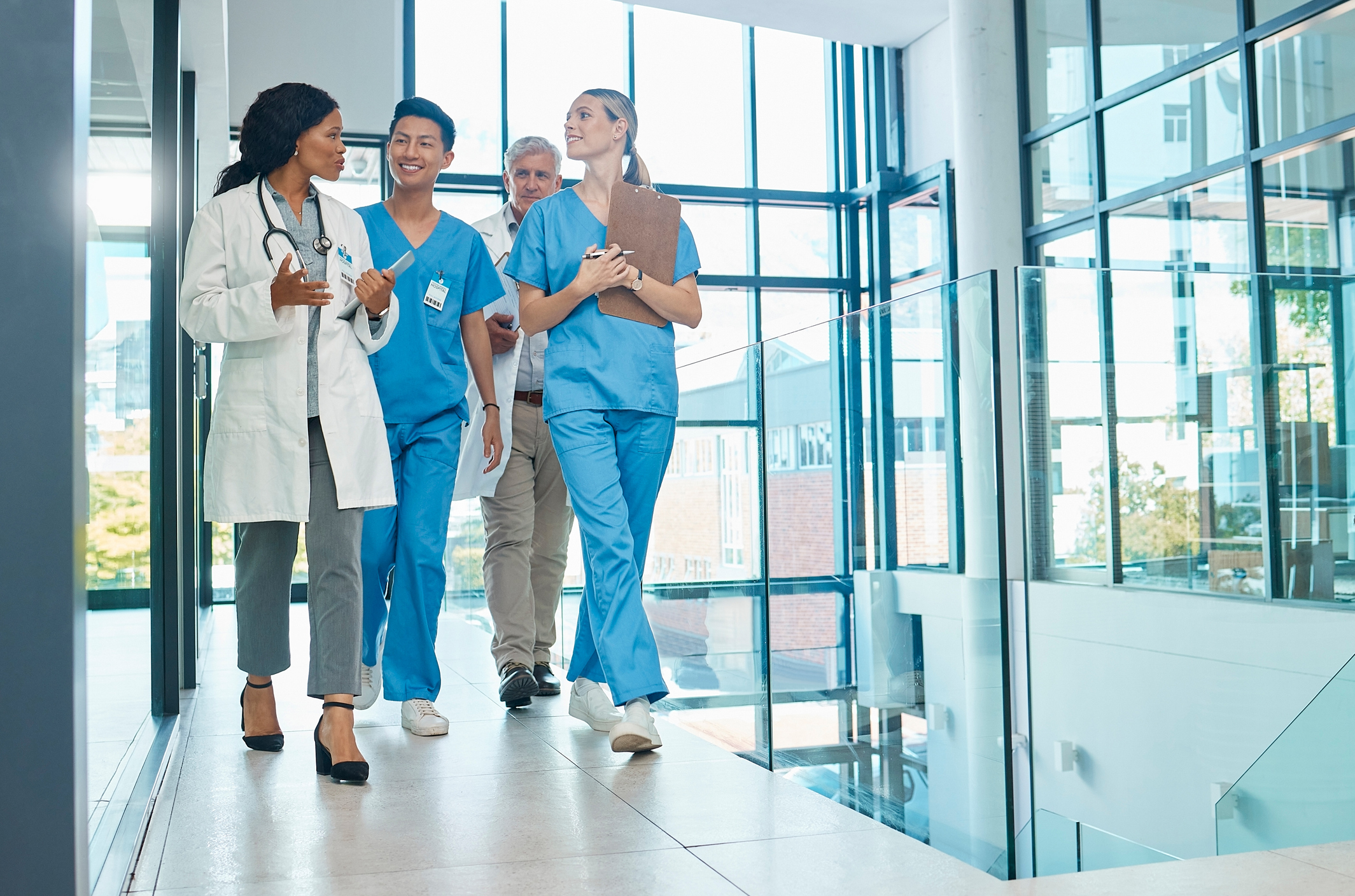 two male doctors and two female doctors walking and having a discussion in a hospital hallway