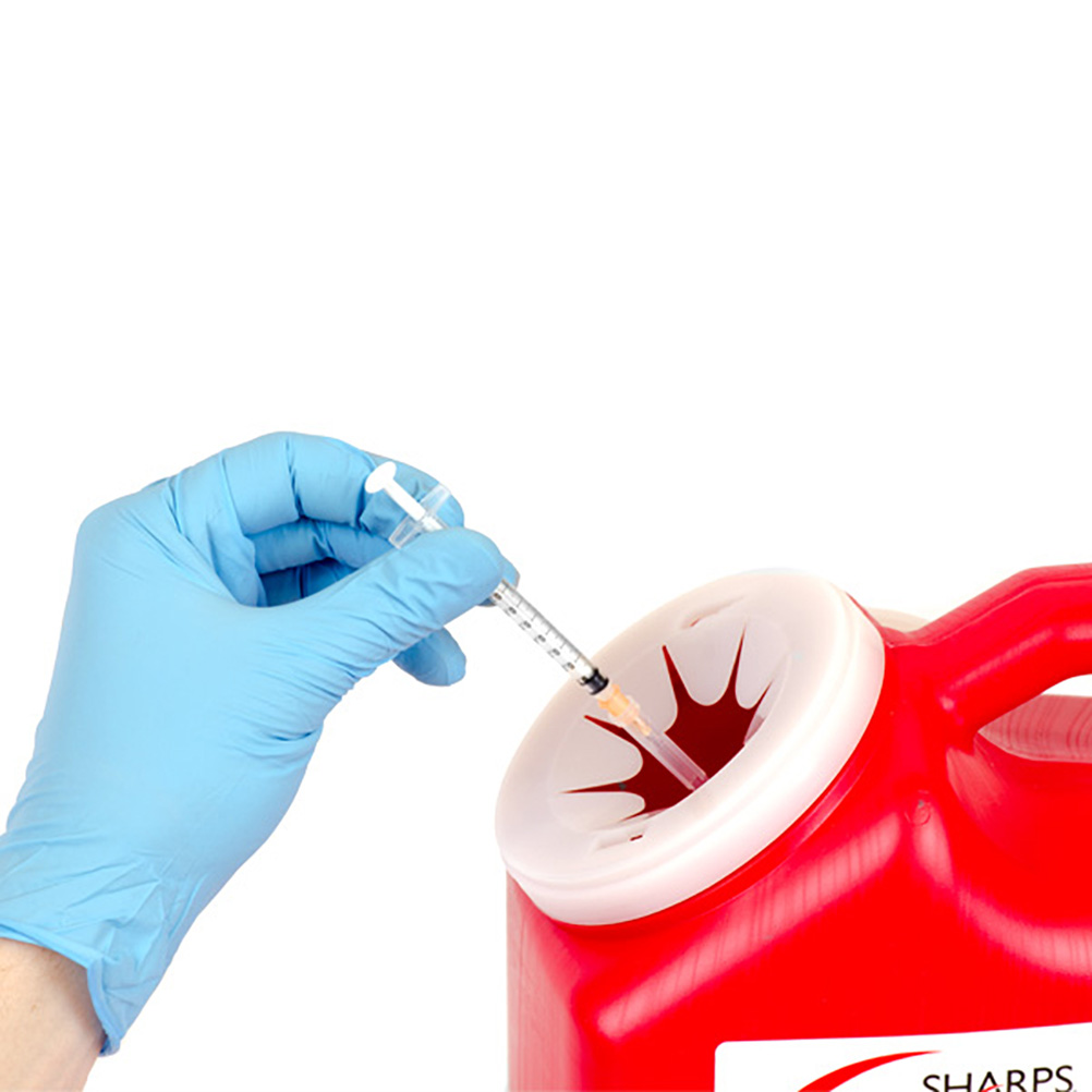 Gloved hand inserting used vial into a red Sharps medical waste container